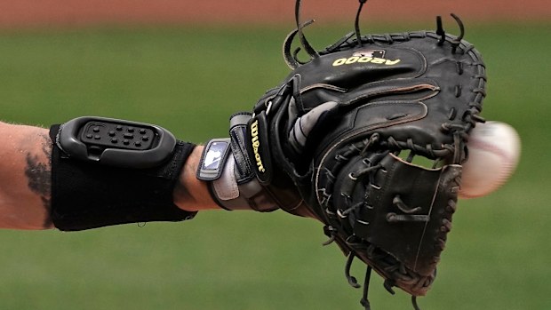 Seattle Mariners catcher Tom Murphy wears a wrist-worn device used to call pitches during a spring training baseball game.