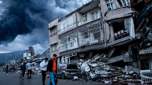 People walk past collapsed buildings in Iskenderun, Turkey.