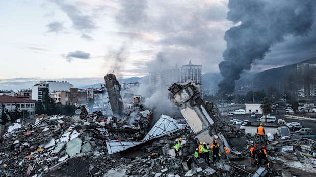 Smoke billows from the Iskenderun Port as rescue workers work at the scene of a collapsed building.