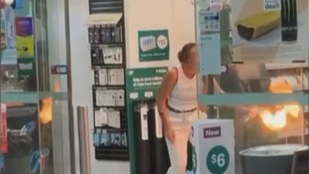 Footage shows the woman directing flames, allegedly created with an aerosol can and a lighter, at a staff member's face, before lighting up a pile of wood inside the shop.