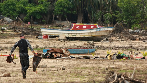 In this photo supplied by the Royal Australian Navy, a sailor from HMAS Supply clears debris on Nomuka Island, Tonga on Feb. 26, 2022. Three months on from a devastating volcano and tsunami in Tonga, the AP checks in on how the island nation is recovering. The bill from the tsunami is estimated at some $90 million and GDP is expected to fall by more than 7% this year. The cleanup has been hindered by an internet outage caused by the tsunami and the nations first outbreak of COVID-19. (LSCSO Rye 