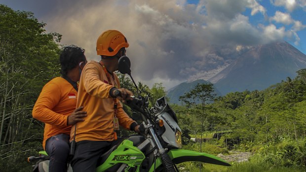 Men watch as Mount Merapi releases volcanic materials during an eruption in Sleman, Indonesia, Saturday, March 11, 2023. 