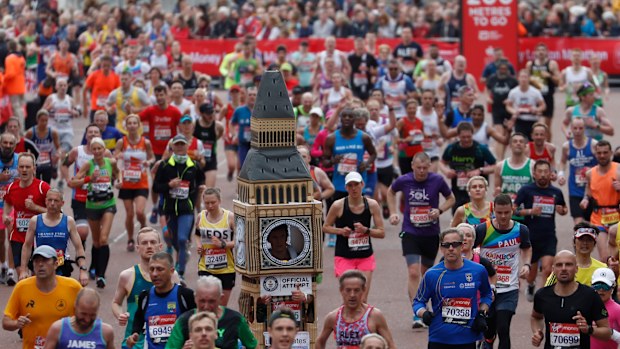 Lukas Bates wearing a costume of Big Ben runs with the crowd towards the finish line of the 39th London Marathon in London, Sunday, April 28, 2019.