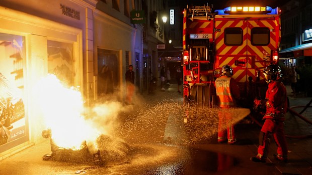 Firefighters work to extinguish a burning container as unrest continues following the death of Nahel, a 17-year-old teenager killed by a French police officer in Nanterre during a traffic stop, and against police violence, in Paris, France, July 1, 2023. REUTERS/Juan Medina