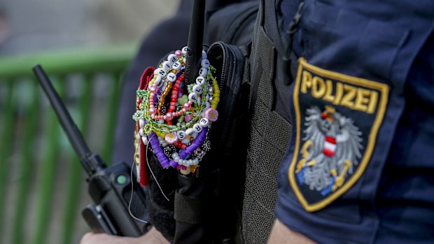 A police officer is decorated with Taylor Swift bracelets while guarding the city centre in Vienna on August 8, 2024. 