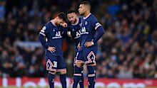Kylian Mbappe of Paris Saint-Germain looks on as teammates Lionel Messi and Neymar talk in the background.