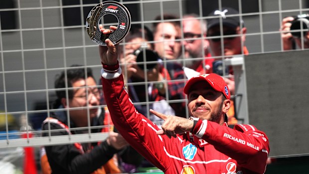 Ferrari driver Lewis Hamilton of Britain holds up the trophy to celebrate winning the sprint race of the Formula One Chinese Grand Prix at the Shanghai International Circuit.