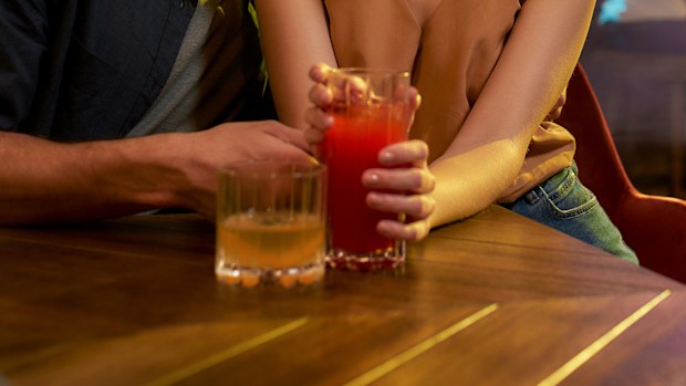 Young man and woman flirting in the bar, enjoying drinks and conversation.