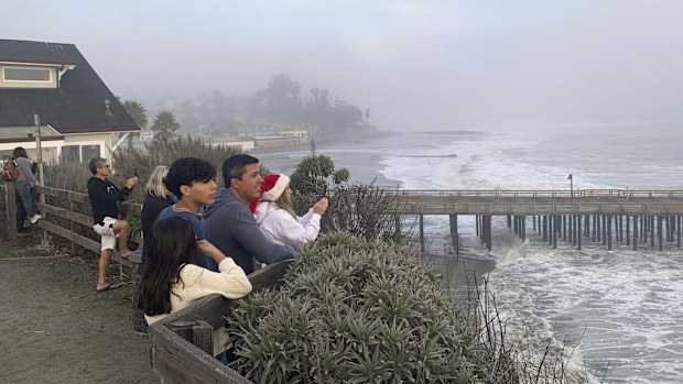 Spectators watch high surf roll in near the Capitola Wharf, Monday, Dec. 23, 2024, in Capitola, Calif. (AP Photo/Pamela Hassell)