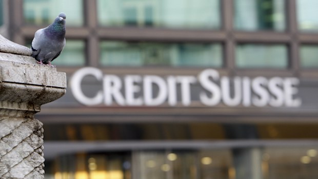 FILE - A pigeon rests near a building hosting offices of Credit Suisse bank in Milan, Tuesday, Oct. 27, 2009. 