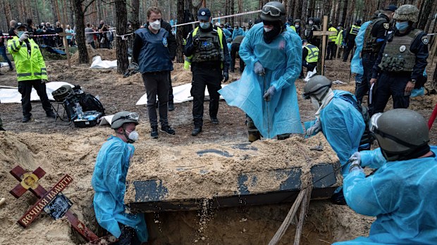 Emergency workers move a body during the exhumation in the recently retaken area of Izium, Ukraine, Friday, Sept. 16, 2022. 