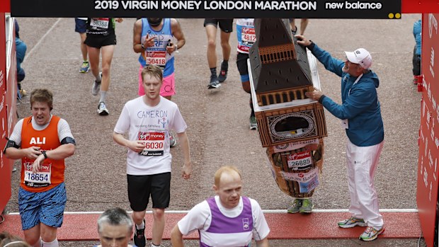 Mr Bates is helped by an official as he attempts to get past the finishing line, during the 39th London Marathon in London, Sunday, April 28, 2019. 