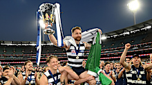 Zach Tuohy of the Cats holds aloft the premiership cup as he is chaired off the field after winning the 2022 AFL Grand Final.