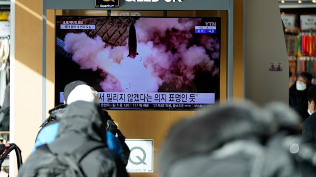 People watch a TV screen showing a news program reporting about North Korea's missile launch.