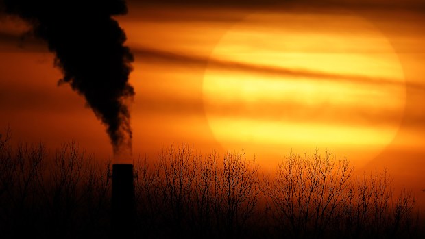 Emissions from a coal-fired power plant are silhouetted against the setting sun