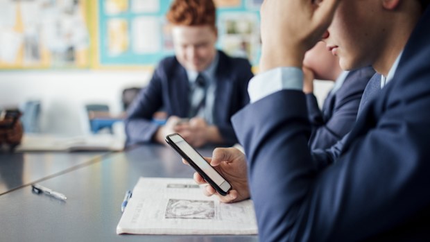 Bored male student using phone during a class teen on mobile boys smart phones
