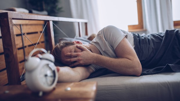 Sleeping man disturbed by alarm clock early in the morning
