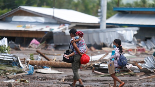 Residents walk beside remains of damaged homes at Maguindanao's Datu Odin Sinsuat town, southern Philippines on Sunday Oct. 30, 2022. Victims of a huge mudslide set off by Tropical Storm Nalgae in a coastal Philippine village that had once been devastated by a killer tsunami mistakenly thought a tidal wave was coming and ran to higher ground toward a mountain and were buried alive, an official said Sunday. (AP Photo)