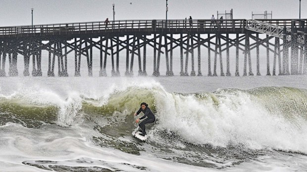 A surfer rides a wave at Seal Beach, Calif., Monday, Dec. 23, 2024. (Jeff Gritchen/The Orange County Register via AP)