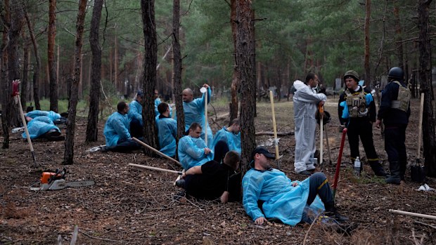Emergency workers have a rest during the exhumation of bodies in the recently retaken area of Izium, Ukraine, Friday, Sept. 16, 2022. 