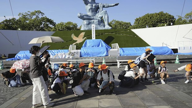 Visitors to the Peace Park crouch as an earthquake alert was issued in Nagasaki, western Japan, Thursday, Aug. 8, 2024 