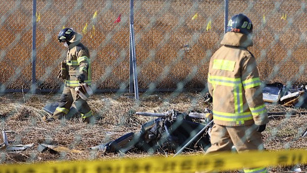 Firefighters search near the debris at the site of a plane fire at the Muan International Airport in Muan, South Korea,
