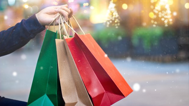 Christmas shopping - shopping bags in hand with snowflake on christmas decoration and lighting on street background