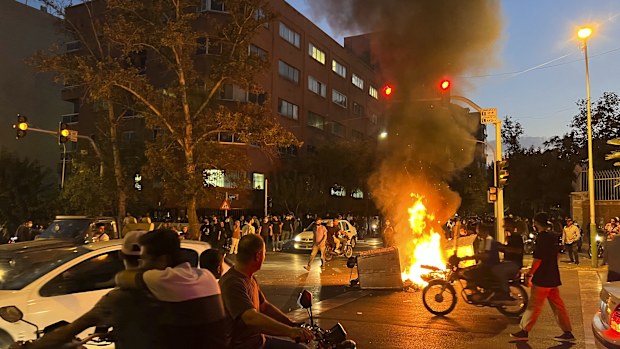 In this Monday, Sept. 19, 2022, photo taken by an individual not employed by the Associated Press and obtained by the AP outside Iran, a police motorcycle and a trash bin are burning during a protest over the death of Mahsa Amini, a 22-year-old woman who had been detained by the nation's morality police, in downtown Tehran, Iran.