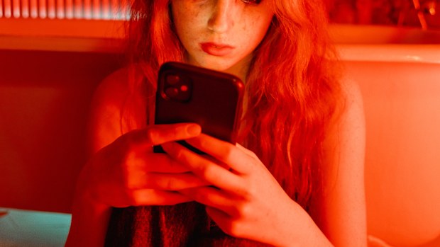 Woman cried looking at her phone in a red room.