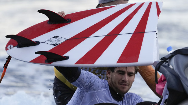 Australia's Jack Robinson rides on the back of a jet ski after breaking his board during a training session.