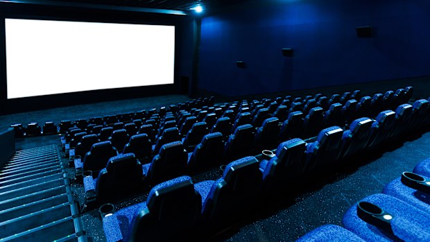 Empty movie theatre interior with screen and seats.