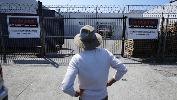 A man stands outside a business where federal immigration authorities conducted an operation.