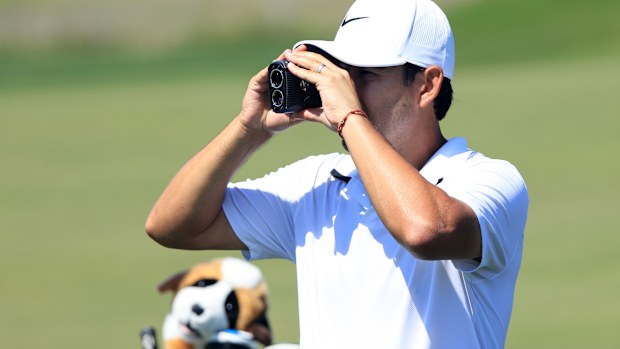 Tour caddie Harry Diamond uses a rangefinder during a practice round.