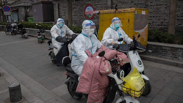 BEIJING, CHINA - MARCH 25: Health workers wear protective suits as they ride scooters in a traditional courtyard neighborhood where they were performing nucleic acid tests to detect COVID-19 on local residents on March 25, 2022 in Beijing, China. China has stepped up efforts to control a recent surge in coronavirus cases across the country, locking down the entire province of Jilin and the city of Shenyang and putting others like Shenzhen and Shanghai under restrictions. Local authorities across