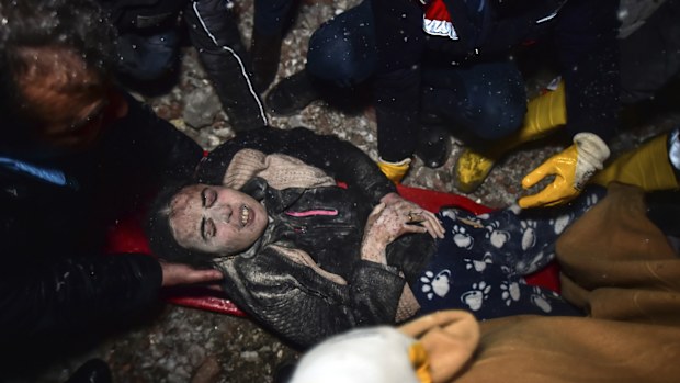 Rescue workers and medics carry a woman out of the debris of a collapsed building in Elbistan, Kahramanmaras, in southern Turkey.