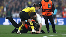 Marcel Sabitzer of Borussia Dortmund assists members of security as they stop a pitch invader.