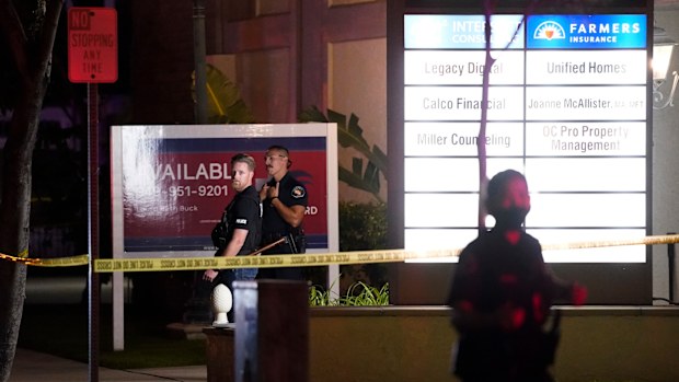 Police officers stand outside a business building where a shooting occurred in Orange. Four people are dead, including a child.