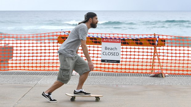 A man on a skateboard is seen going past the closed off Surfers Paradise beach on the Gold Coast, in April.