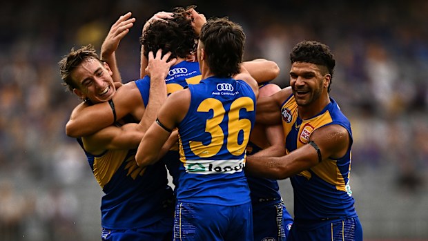 Tom Barrass of the Eagles celebrates with his teammates after kicking his first career goal.