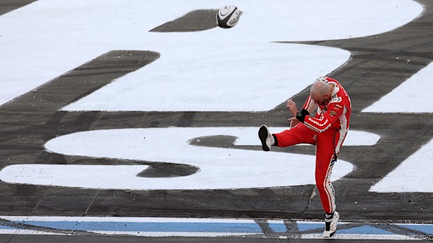Shane Van Gisbergen kicks a rugby ball in celebration after winning at Charlotte Motor Speedway.