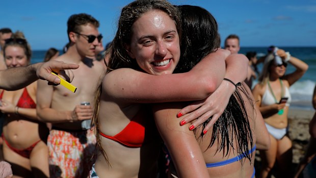 Two spring break revelers hug while partyng in a large crowd on the beach, Tuesday, March 17, 2020, in Pompano Beach, Fla. 