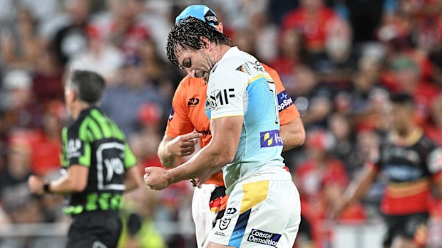 Kieran Foran of the Titans is assessed by the trainer after injuring his arm against the Dolphins.