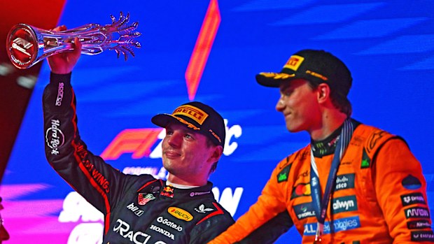 Second placed Max Verstappen lifts his trophy on the podium during the F1 Grand Prix of Saudi Arabia next to winner Oscar Piastri.