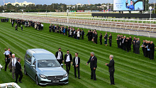 A guard of honour is formed as the hearse goes down the Flemington straight during a funeral service for jockey Dean Holland.
