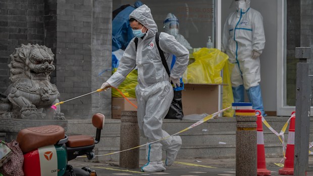 BEIJING, CHINA - MARCH 22: A health worker wears a  protective suit as he disinfects the area near a nucleic acid testing site to detect COVID-19 in the street on March 22, 2022 in Beijing, China. China has stepped up efforts to control a recent surge in coronavirus cases across the country, locking down the entire province of Jilin and the city of Shenyang and putting others like Shenzhen and Shanghai under restrictions. Local authorities across the country are mass testing as China tries to ma