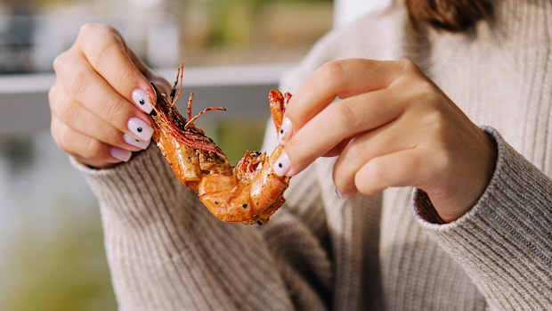 woman eating big fried king prawn