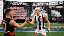 Zach Merrett and Darcy Moore shake hands before leading their teams through a joint banner.