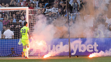 Victory goalkeeper Paul Izzo picks up flares during an A-League Men's match between Melbourne City and Melbourne Victory.