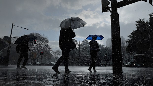 People protect themselves with umbrellas during a rain shower in the centre of Sydney