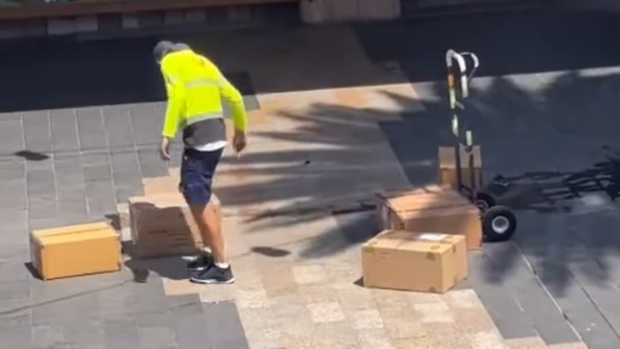 An Australia Post employee has come under fire after he was filmed hurling delivery boxes outside a retail store. 
